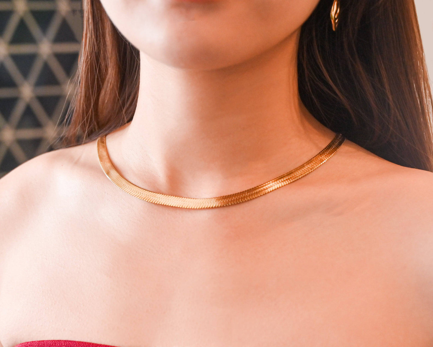 A woman in off-shoulder red top wearing the 18K Gold Herringbone Necklace