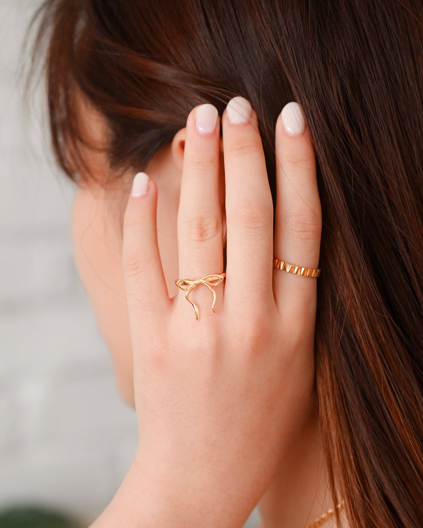 A woman in white off-shoulder top wearing the Thin Bow Tie Ring