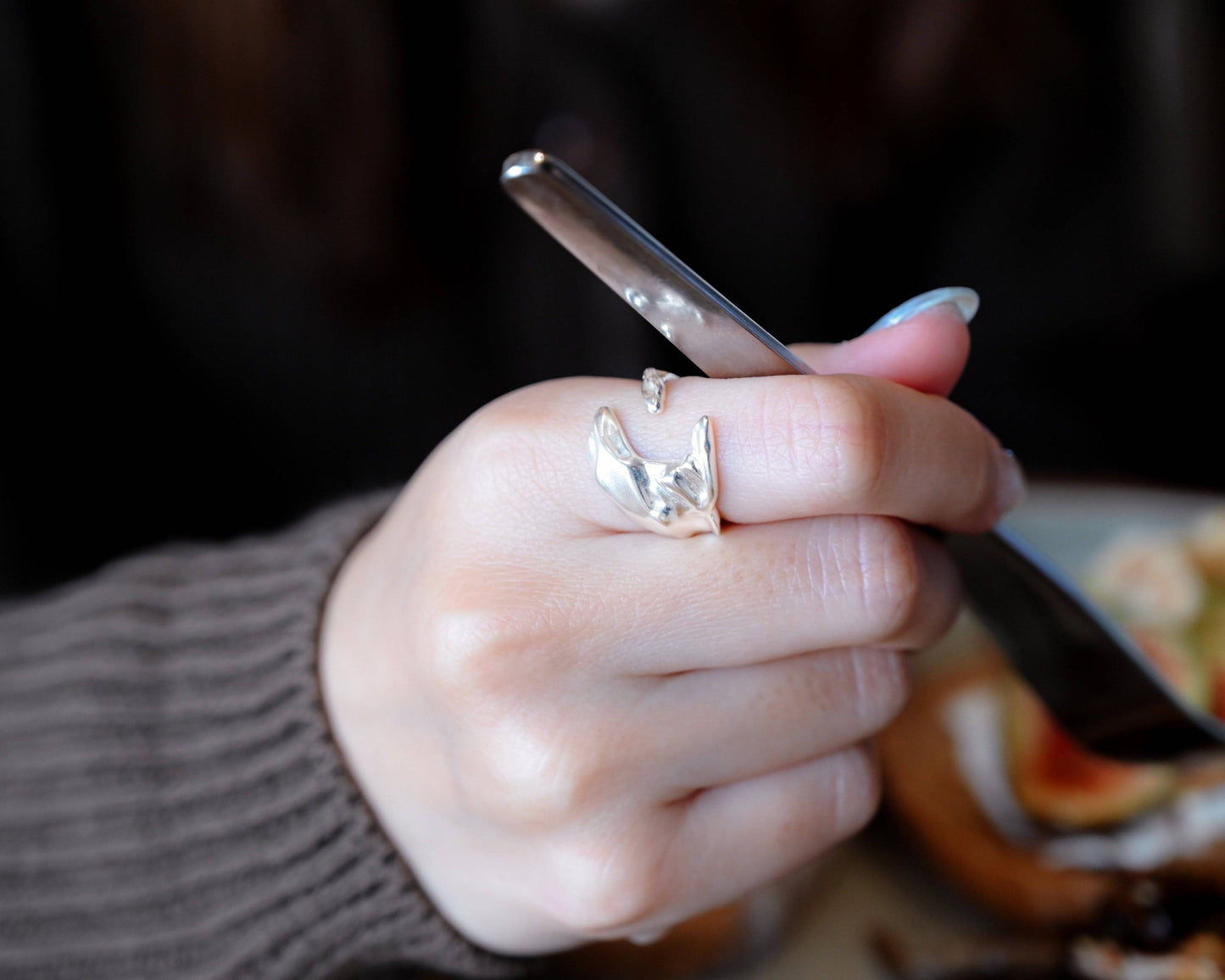 A woman wearing the Sterling Silver Whale Tail Ring and holding a folk