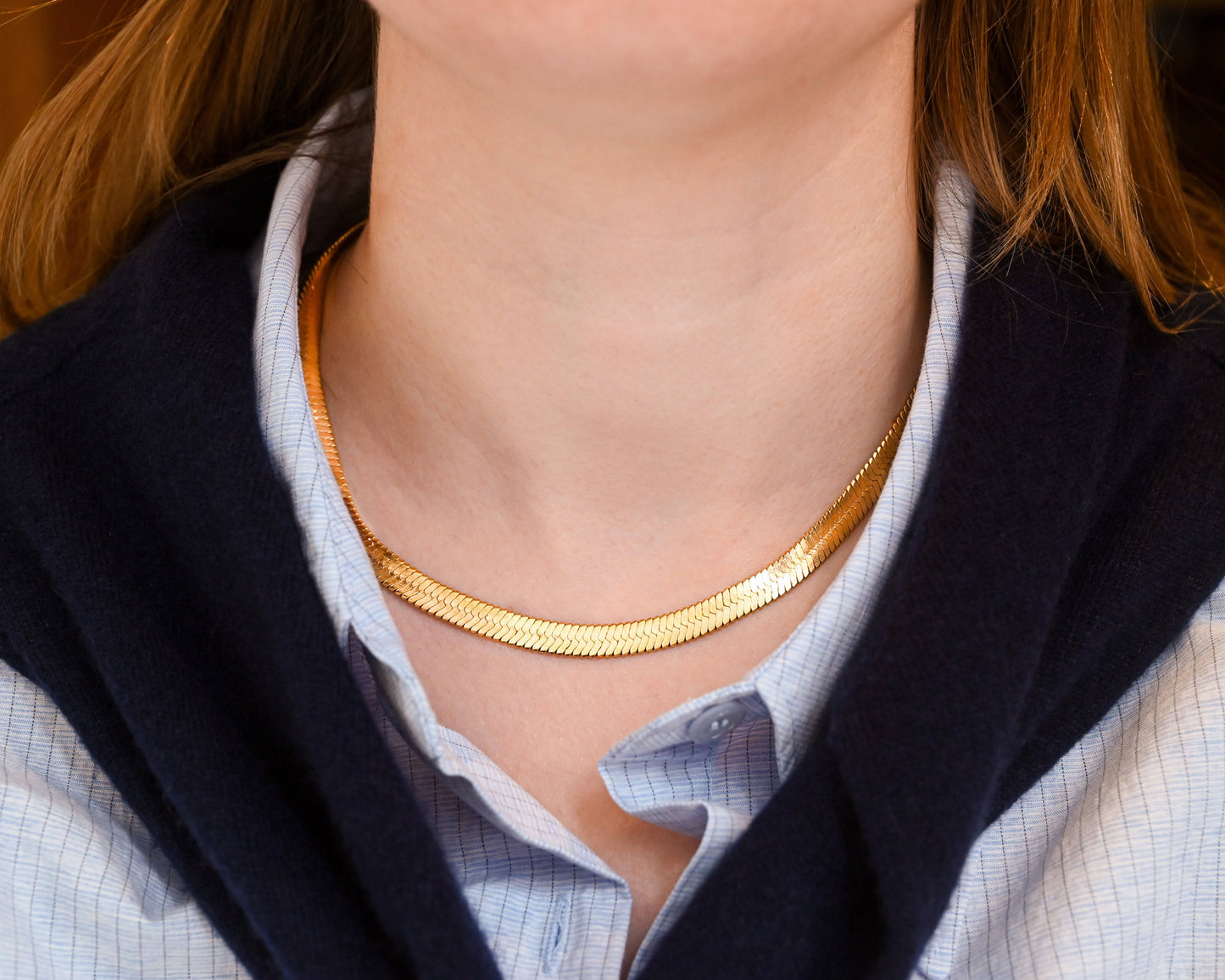 A woman in blue shirt wearing the 18K Gold Herringbone Necklace