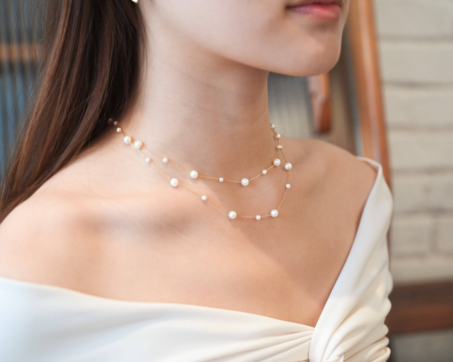 A woman wearing white off-shoulder top with the Double Layer Pearl Cascade Necklace