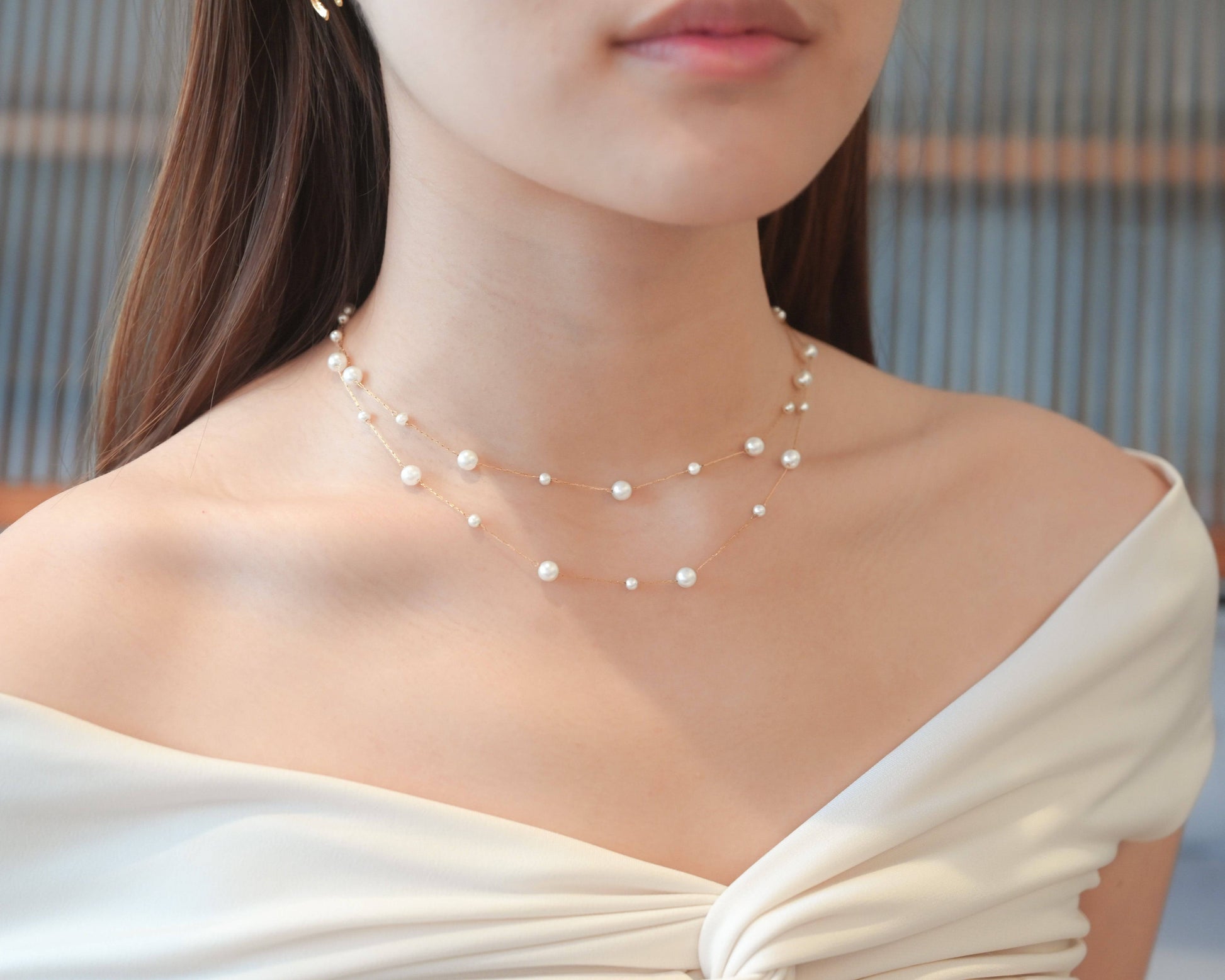 A woman wearing white off-shoulder top with the Double Layer Pearl Cascade Necklace