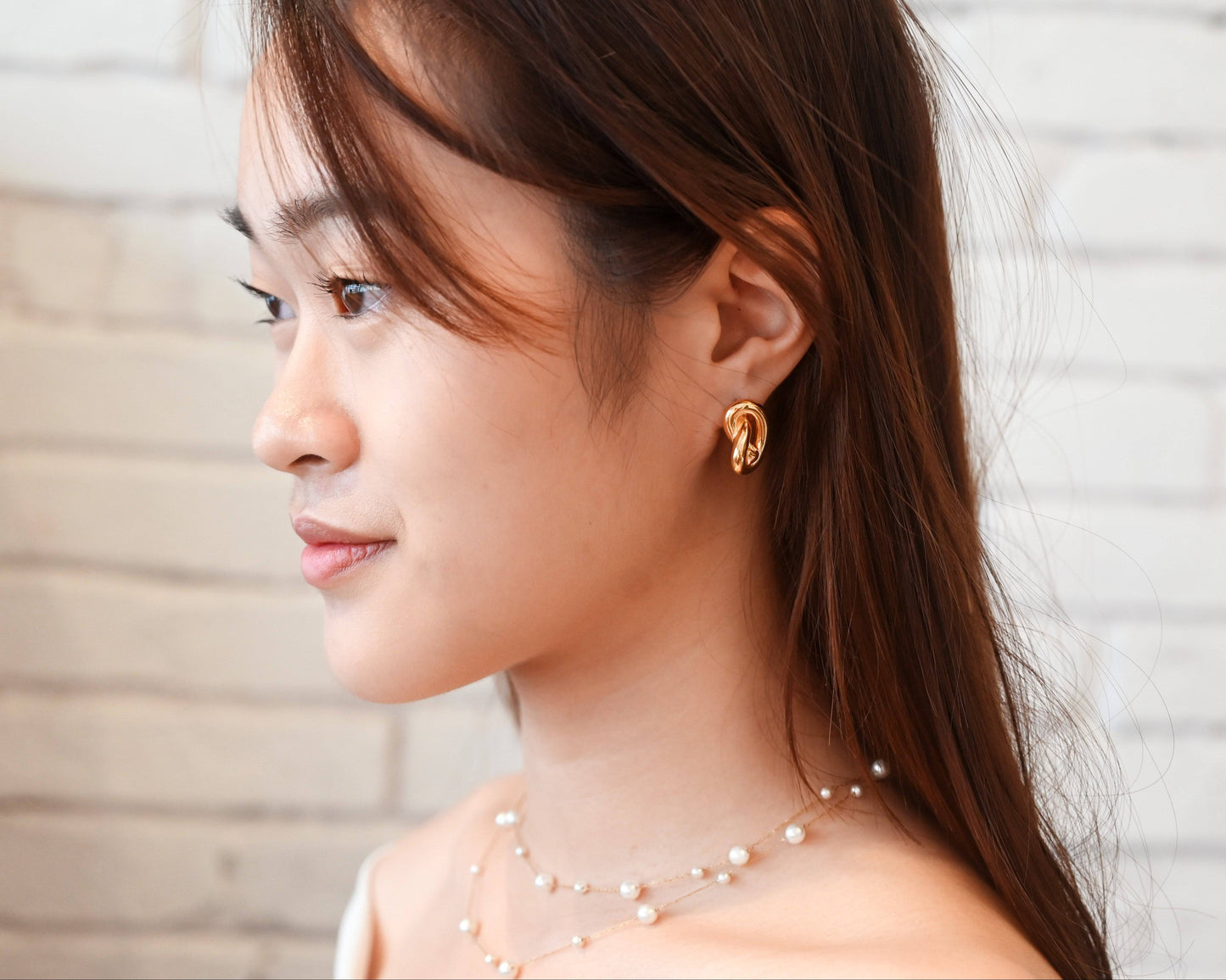 A woman wearing white off-shoulder top with the Double Layer Pearl Cascade Necklace