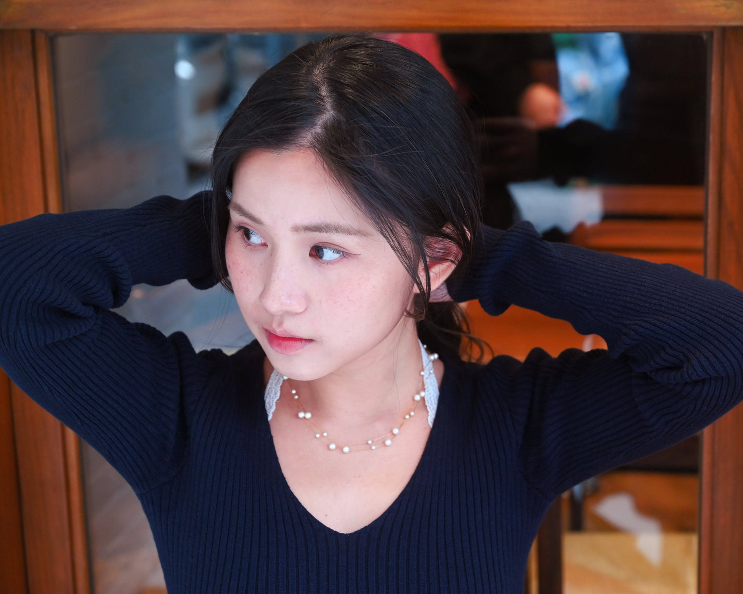 A woman wearing navy blue sweater with the Double Layer Pearl Cascade Necklace